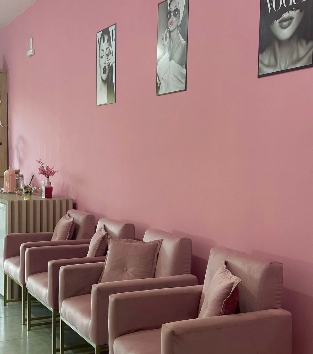 Recepção com parede rosa, poltronas de veludo rosa e quadros
